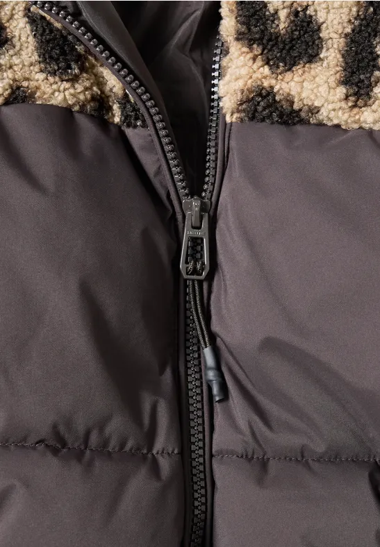 Nahaufnahme einer gefütterten Jacke mit schwarzem Reißverschluss und beigem Teddy-Fleece mit schwarzen Flecken.