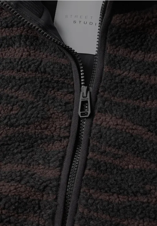 Gros plan d'une veste polaire brun-noir à motif, avec fermeture éclair et étiquette intérieure.