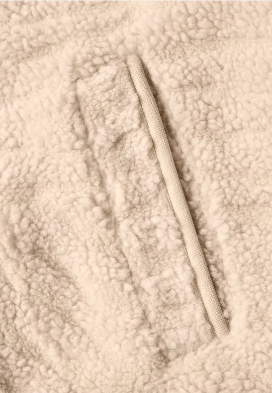 Gros plan d’un tissu polaire d’agneau beige avec couture et poche zippée