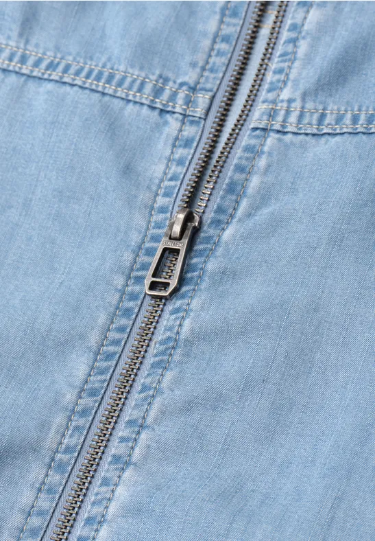 Close-up van een gesloten metalen ritssluiting op lichtblauw denim.