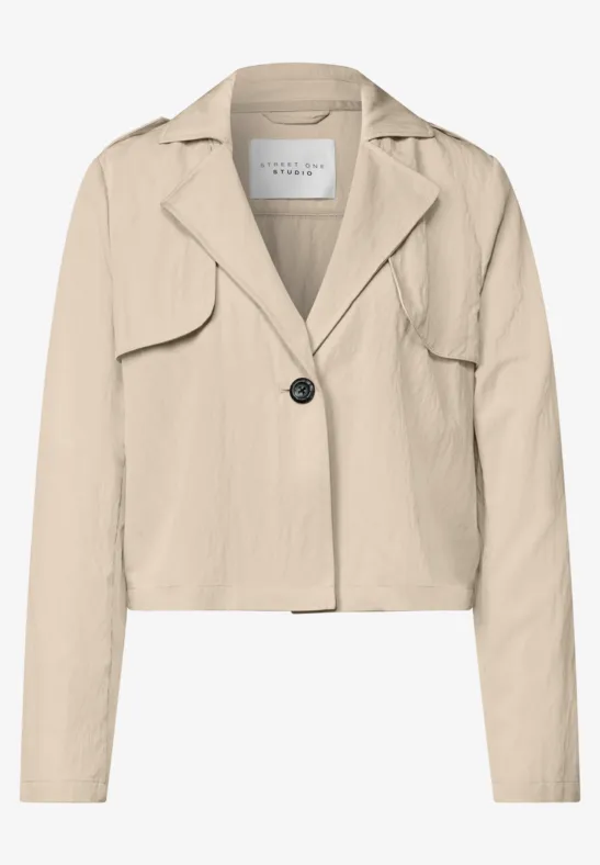 Een kort gesneden, beige blazer met reverskraag, een knoopsluiting en lange mouwen.