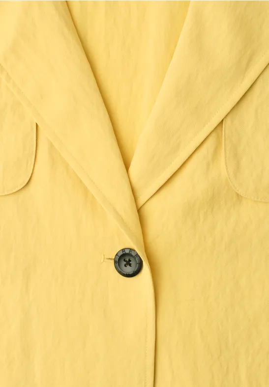 Gelbes Blazer-Sakko mit Revers und schwarzem Knopf in Nahaufnahme.