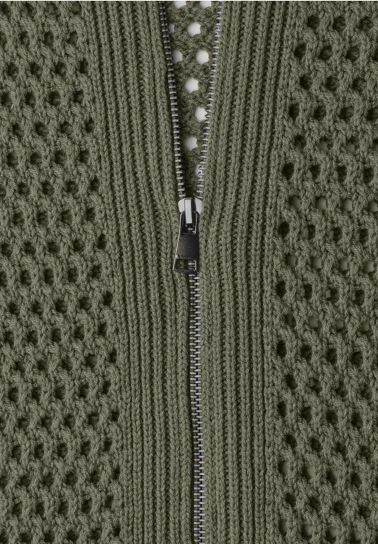 Nahaufnahme eines grünen Strickstoffs mit Reißverschluss in der Mitte.