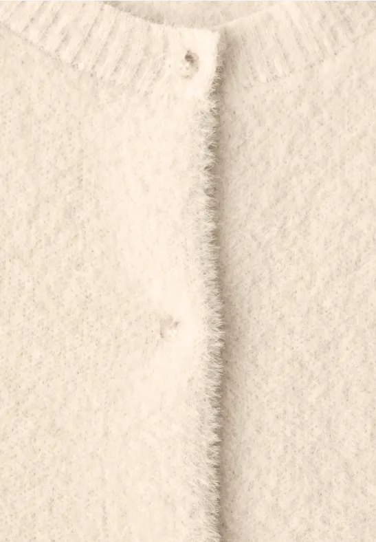Nahaufnahme eines cremeweißen, flauschigen Cardigans mit Rundhalsausschnitt und Knopfleiste.