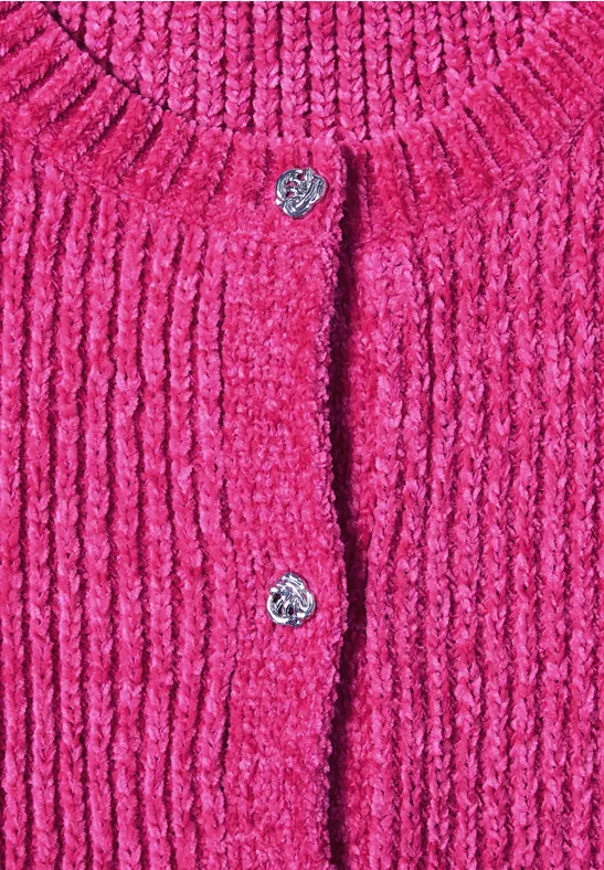 Nahaufnahme eines leuchtend pinken, grob gestrickten Cardigans mit silbernen Blumenknöpfen.