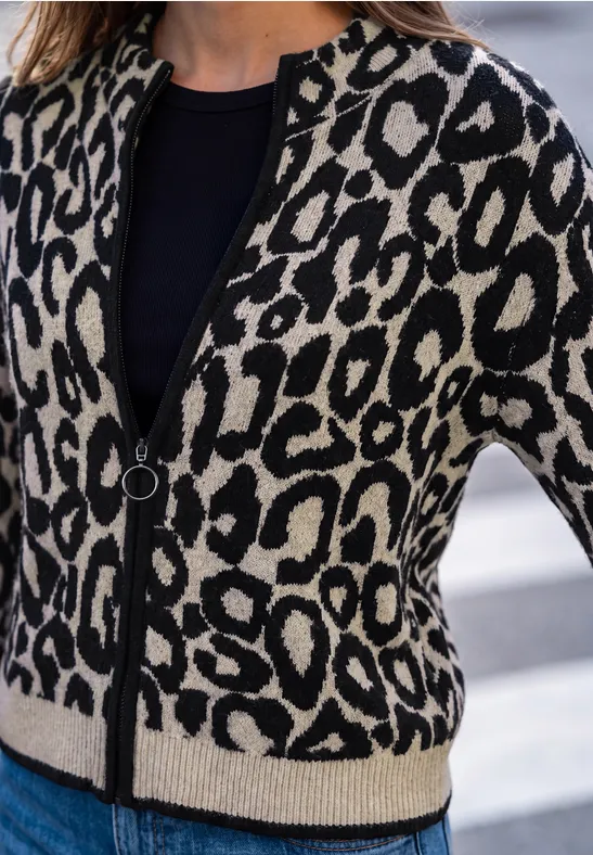 Frau trägt eine schwarz-beige Strickjacke im Leopardenmuster über einem schwarzen Top und Jeans.