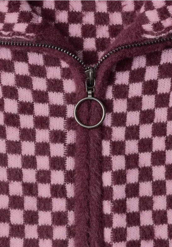 Nahaufnahme eines würfelförmigen karierten Fleece-Stoffes in Rosa und Dunkelrot mit einem Reißverschluss.