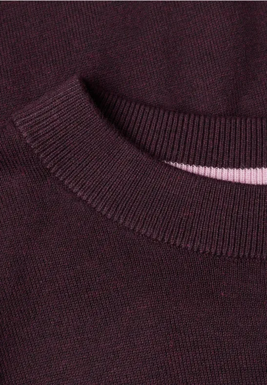 Nahaufnahme eines burgunderfarbenen Strickpullover-Kragens mit geripptem Abschluss und dezentem rosa Innenband.