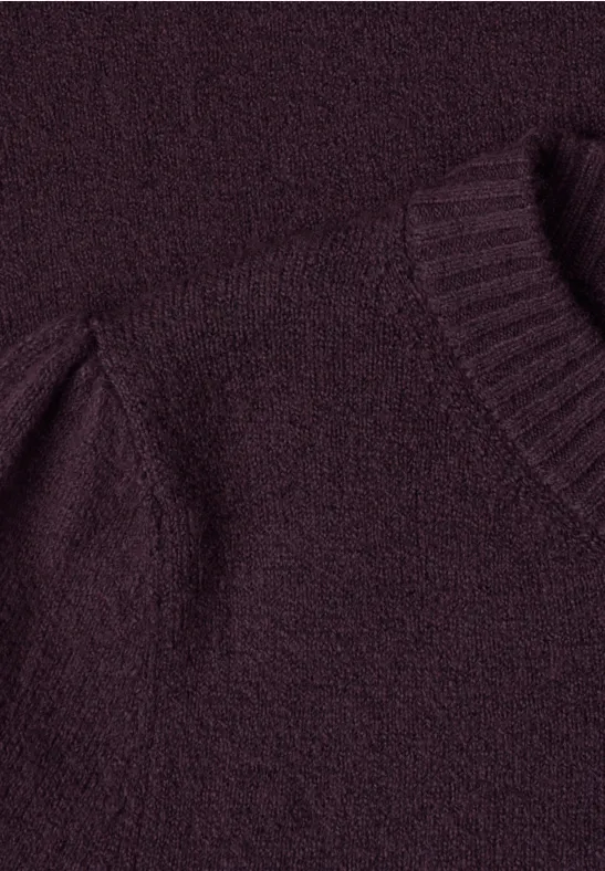Gros plan sur un pull en maille bordeaux en tissu doux et duveteux.