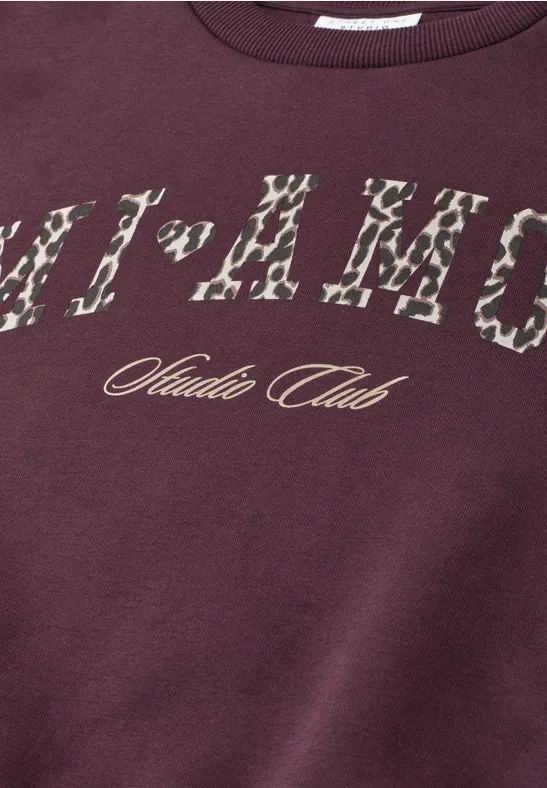 Bordeauxrotes Sweatshirt mit Animal-Print-Schriftzug und ‚Studio Club‘-Logo in Gold.