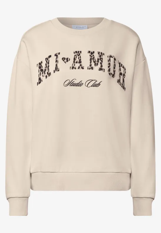 Beiges Sweatshirt mit leo-bedrucktem Schriftzug 'MI+AMOR' und kleinem Schriftzug darunter.