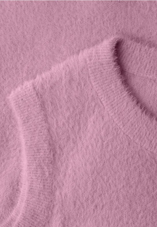 Nahaufnahme eines flauschigen rosa Strickoberteils mit weicher Textur.