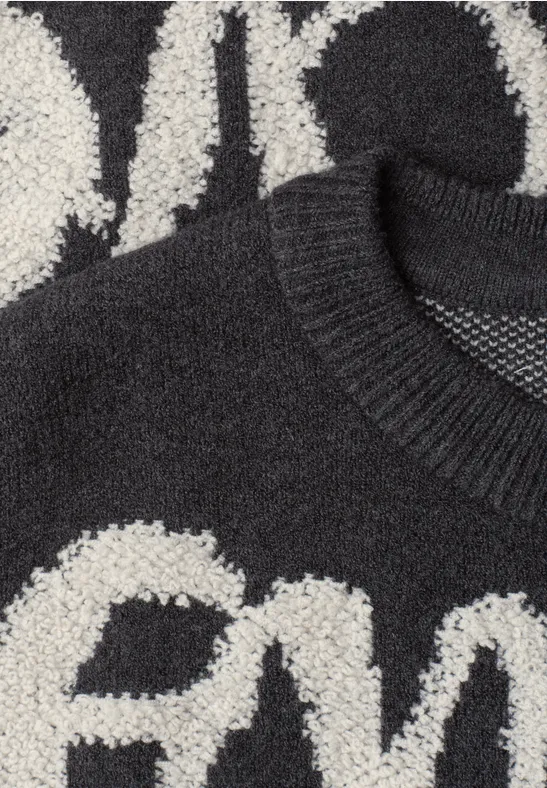 Schwarz-weißer Strickpullover mit kontrastierendem, flauschigem Buchstabenmuster und Rundhalsausschnitt.