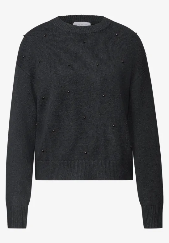 Schwarzer Pullover mit Rundausschnitt und kleinen goldenen Nieten als Akzente.