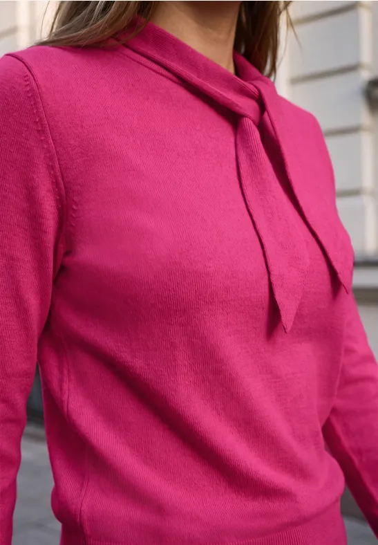 Eine elegante magentafarbene Strickbluse mit langem Arm und schmaler Schleife am Hals.
