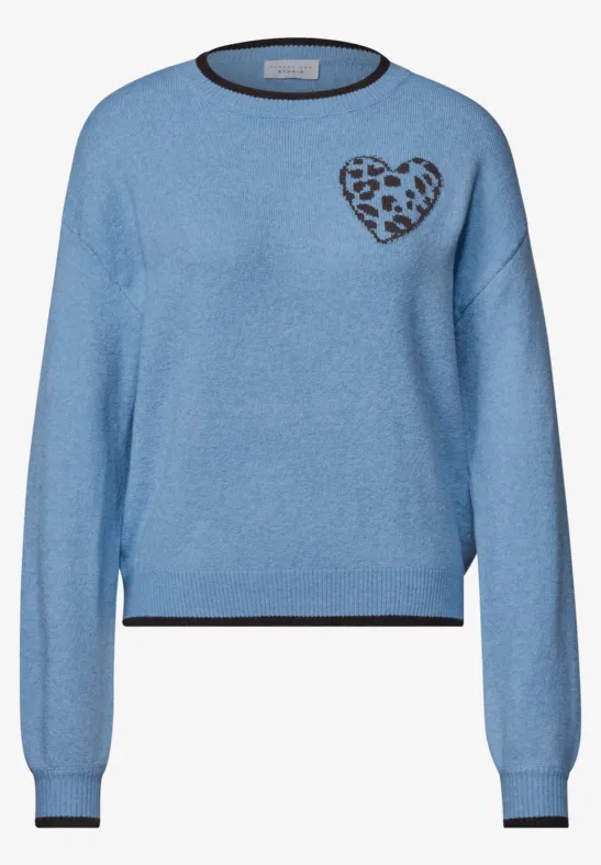 Leicht blauer Pullover mit schwarzem Bund an Ärmeln und Kragen und Herz mit Leopardenmuster auf der Brust.