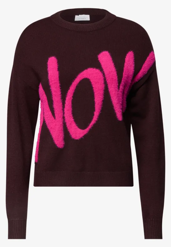 Dunkelroter Pullover mit auffälligem pinkfarbenem Schriftzug „NOW“.