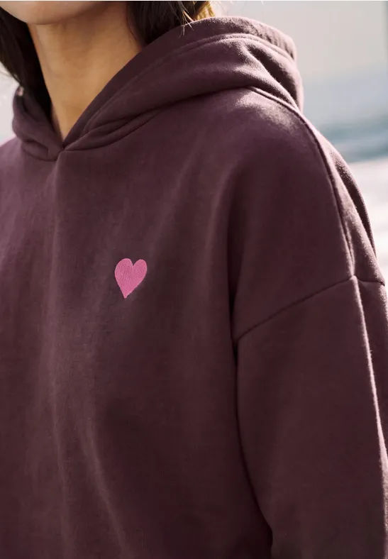 Dunkelrote Kapuzenjacke mit kleinem rosa Herz-Motiv auf der Brust