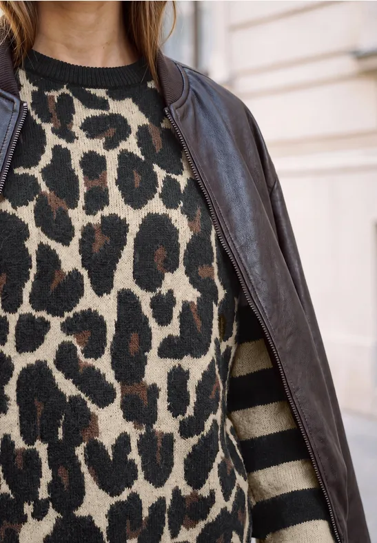 Schwarze Lederjacke über Pullover mit Leopardenmuster und dunkelbeigen Streifen an den Ärmeln