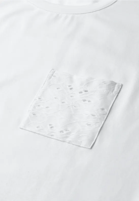Weißes T-Shirt mit Brusttasche in hellem Ton und kleinen Lochmustern.