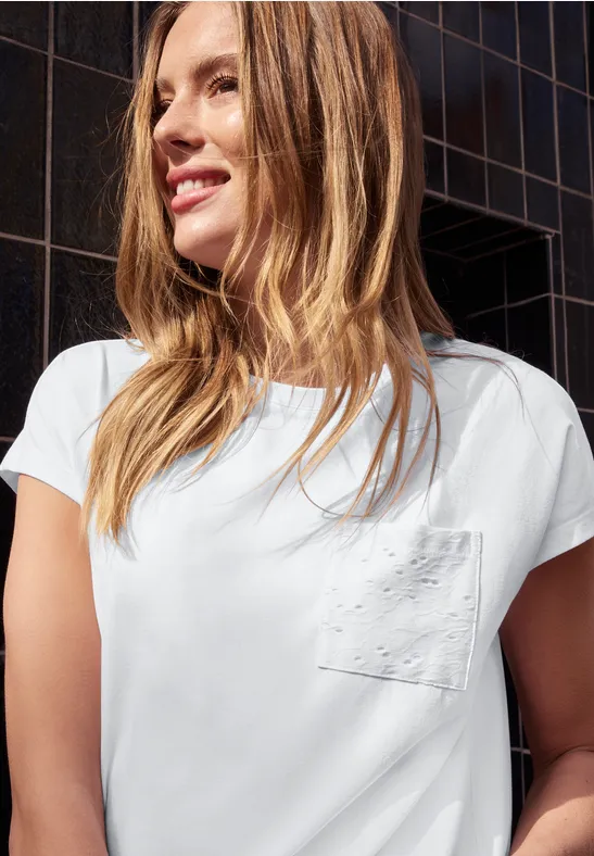 Mädchen mit weißem T-Shirt vor dunkler, gekachelter Fassade