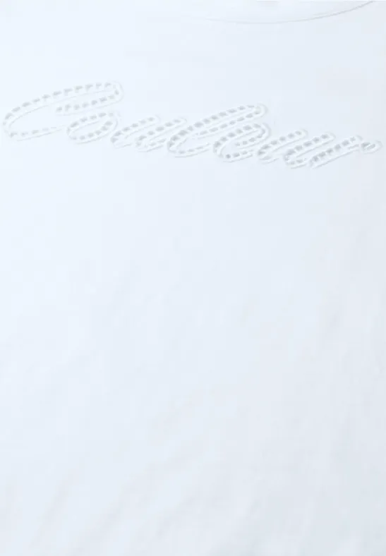 Nahaufnahme eines weißen T-Shirts mit dezentem, gepunktetem Schriftzug in geschwungener Schrift.