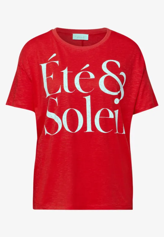 Een rood t-shirt met de witte tekst 'Été & Soleil'.