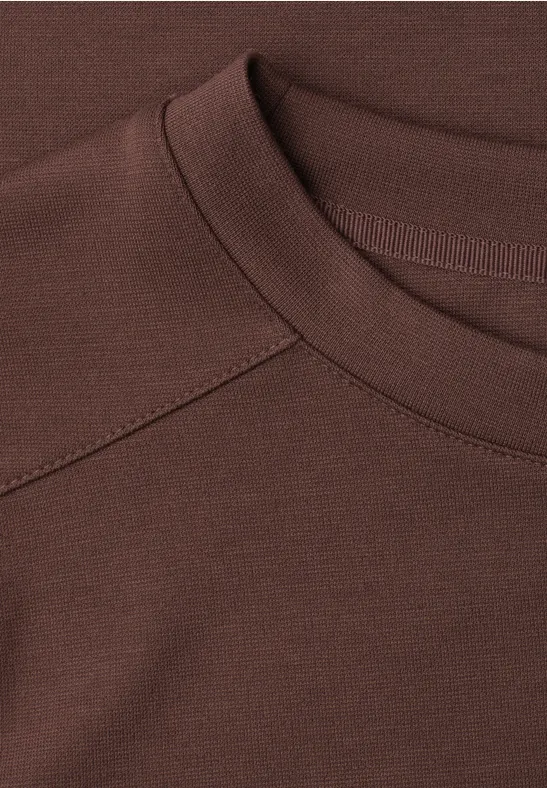 Gros plan d’un col de T-shirt brun foncé avec couture raglan