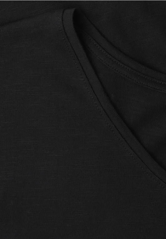 Nahaufnahme eines schwarzen Baumwoll-T-Shirts mit Rundhalsausschnitt und Nahtdetail.