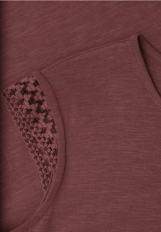 Bruin kledingstuk met afgeronde zak en decoratief pied-de-poule- en haakpatroon.