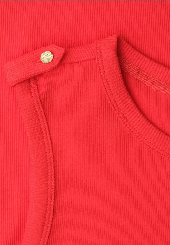 Close-up van rood geribbeld textiel met een goudkleurige knoop op de schouder