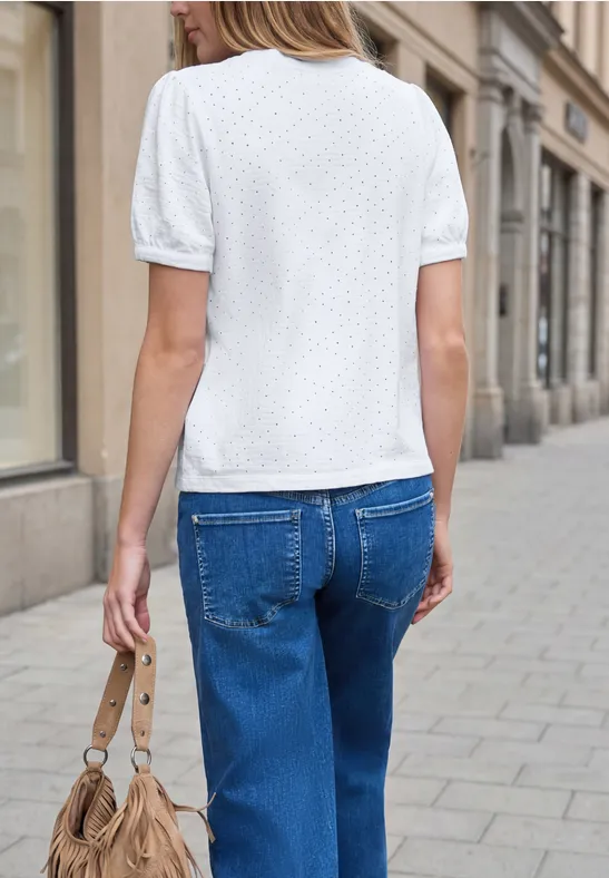 Frau von hinten in weißem Shirt, blauen Jeans und Handtasche auf Bürgersteig.