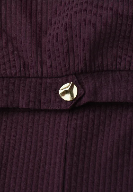 Donkerpaarse geribbelde stof met een goudkleurige driehoekige sierknop ter hoogte van de taille