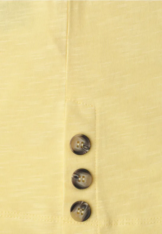 Gelbes Oberteil mit drei braunen Knöpfen in der Knopfleiste