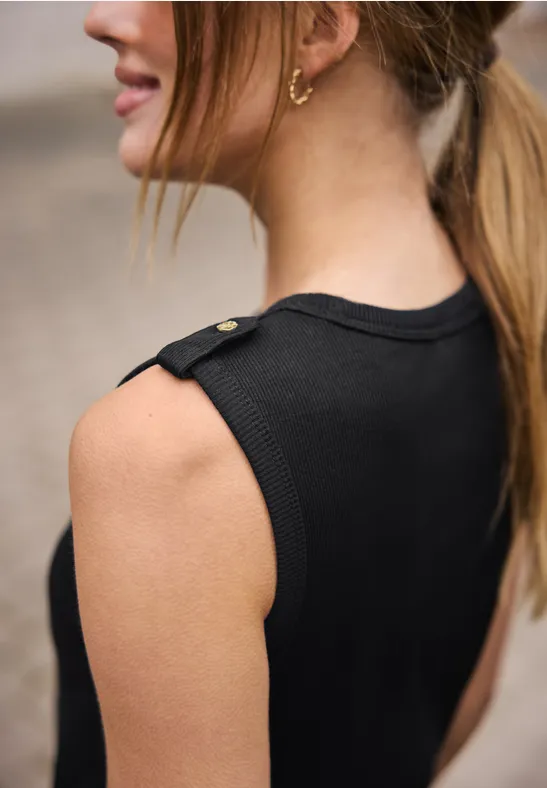 Detailfoto van een vrouw in een zwart mouwloos topje, met focus op schouder, nek en oorbel.