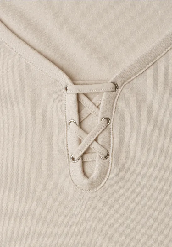 Beige Oberteil mit Schnürung am V-Ausschnitt.