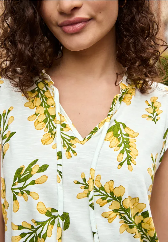 Close-up van vrouw in witte top met geel bloemenpatroon
