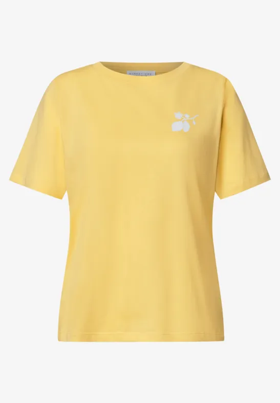 Ein schlichtes gelbes T-Shirt mit kleinem weißen Blumenmotiv auf der Brust.