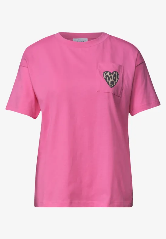 Rosa T-Shirt mit Rundhalsausschnitt, kurzen Ärmeln und Herzmotiv auf der Brusttasche.