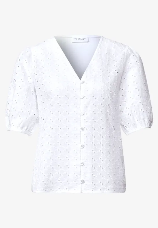 Blouse blanche à col V, empiècements ajourés, manches courtes bouffantes et patte de boutonnage.