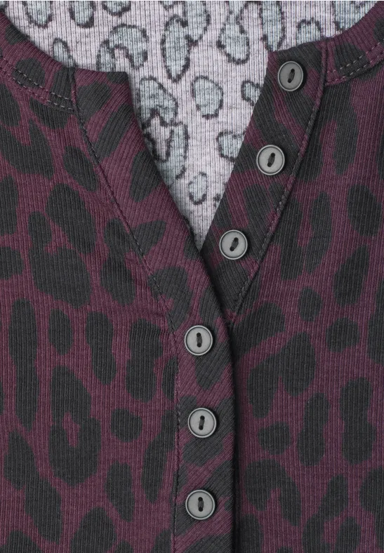 Nahaufnahme eines Pullovers mit violetter Leopardenmuster-Struktur und Knopfleiste