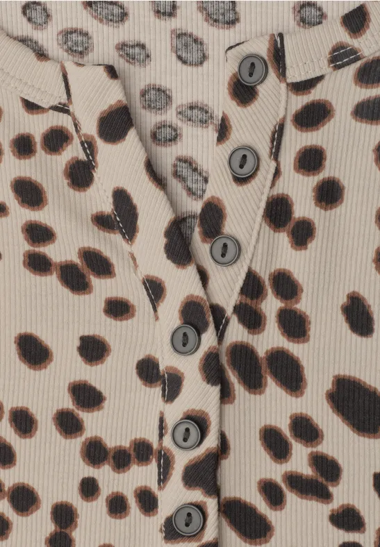 Detailaufnahme eines beigen Oberteils mit schwarzen Leopardenflecken und Knopfleiste.