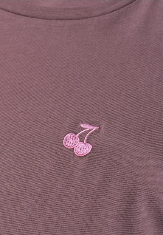 Lila T-Shirt mit kleiner rosa Kirsch-Applikation auf der Brust.