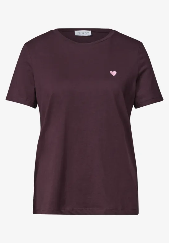 T-shirt violet foncé à manches courtes avec petit écusson cœur rose sur la poitrine.
