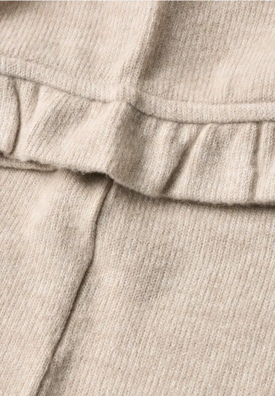 Nahaufnahme eines beigen Strickstoffs mit Rüschendetail