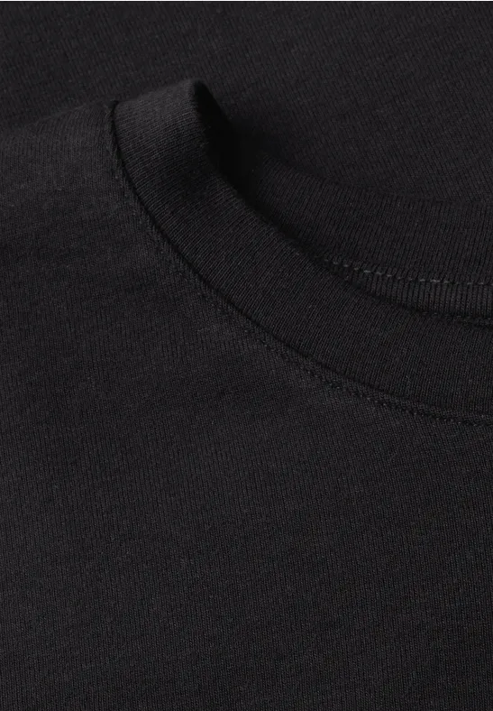 Nahaufnahme eines schwarzen T-Shirts mit Rundhalsausschnitt auf dunklem Hintergrund.