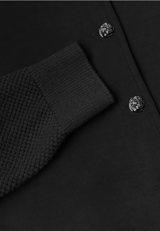 Zwarte gebreide cardigan met geribde mouwboord en decoratieve knopen.
