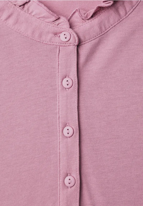 Nahaufnahme eines rosa Baby-Bodys mit Rüschenkragen und Druckknöpfen.
