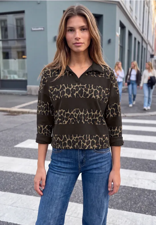 Femme en pull léopard et jean sur un passage piéton en ville.