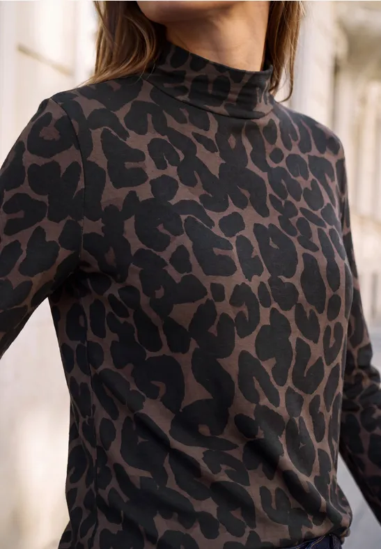 Frau trägt eng anliegendes, braun-schwarzes Shirt mit Leopardenmuster und Rollkragen; Ausschnitt fokussiert Oberkörper.